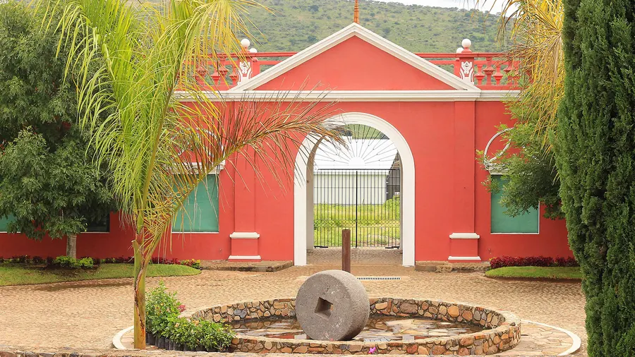 Entrada de una hacienda tequilera con una antigua tahona de piedra